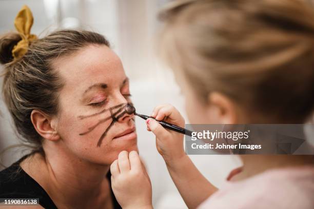 girl painting mothers face - kinderschminken stock-fotos und bilder