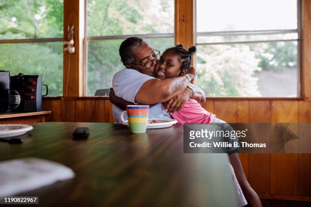 black grandmother hugging granddaughter - típico de clase mediana fotografías e imágenes de stock