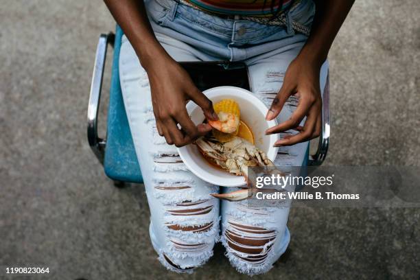 young woman eating seafood boil - ripped jeans stock pictures, royalty-free photos & images