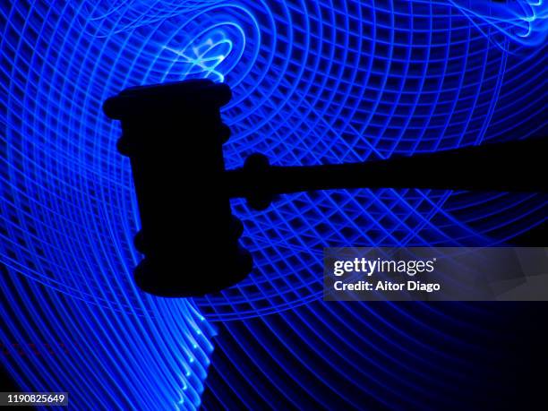 hand with a judge's gavel with in a futuristic networking blue background. - criminal justice concept stock pictures, royalty-free photos & images