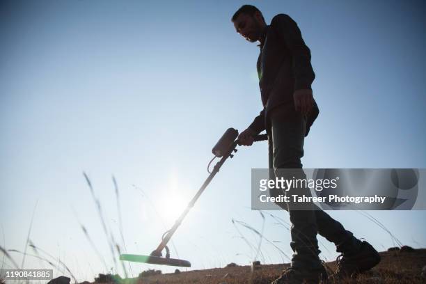a young man using recreational metal detector to find treasure - treasure hunt stock pictures, royalty-free photos & images