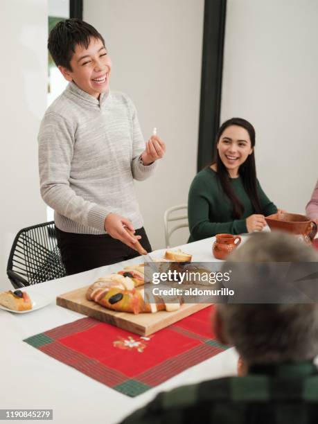niño mexicano feliz sosteniendo la figura de rosca de reyes - rosca de reyes fotografías e imágenes de stock