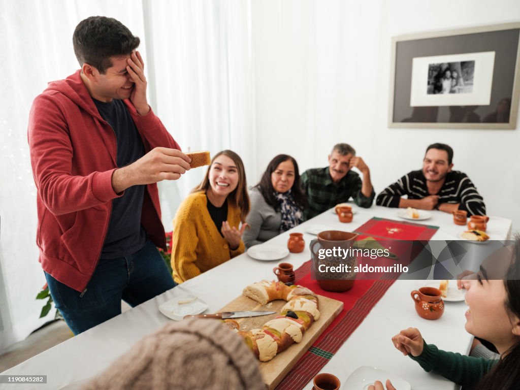 Mexican family celebrating and laughing with rosca de reyes