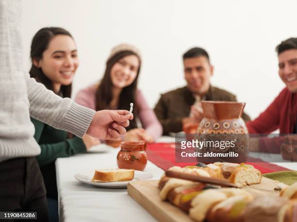 mexican family looking at figurine of rosca de reyes on epiphany day - king cake stock pictures, royalty-free photos & images