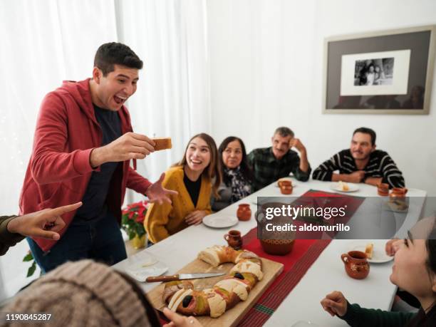 excited latin man holding rosca de reyes with figurine on epiphany - rosca de reyes stock pictures, royalty-free photos & images