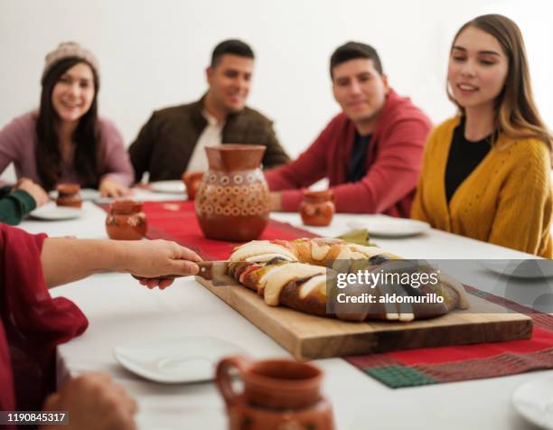 mexicaanse familie snijden traditionele rosca i de reyes aan tafel - roscon de reyes stockfoto's en -beelden