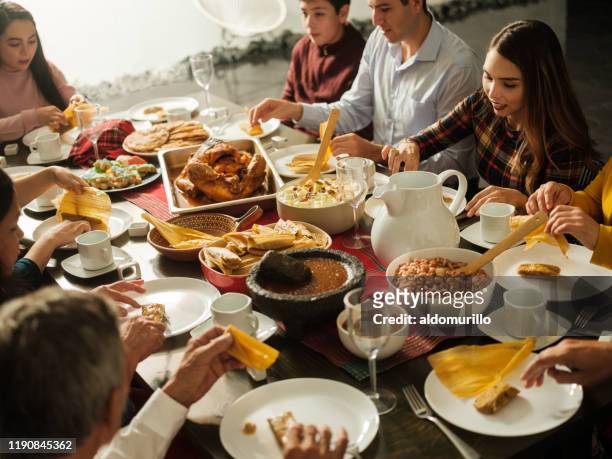 latin people eating traditional mexican food at table - mexican tradition stock pictures, royalty-free photos & images