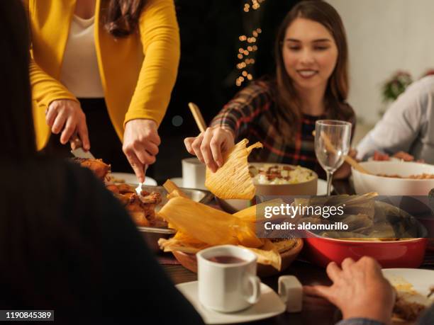 mexican young woman taking food from table - mexican christmas stock pictures, royalty-free photos & images