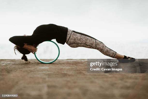 young woman practicing yoga, stretching her back with a roller. - scraped knee stock pictures, royalty-free photos & images