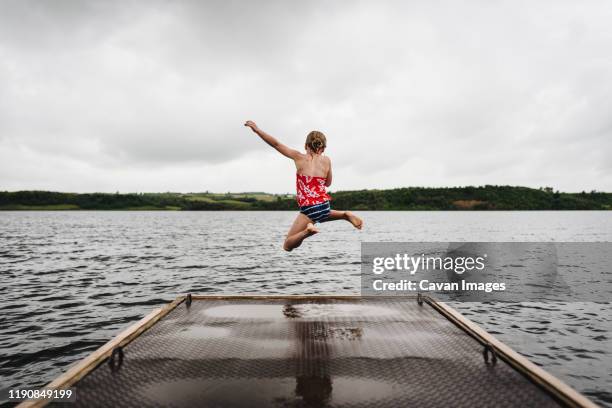 little girl jumps off dock into lake on a cloudy summer day - bismarck north dakota stock-fotos und bilder