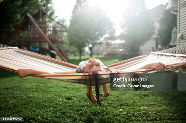 joyful girl 10-12 years old swinging and laughing in hammock outside - backyard hammock stock pictures, royalty-free photos & images