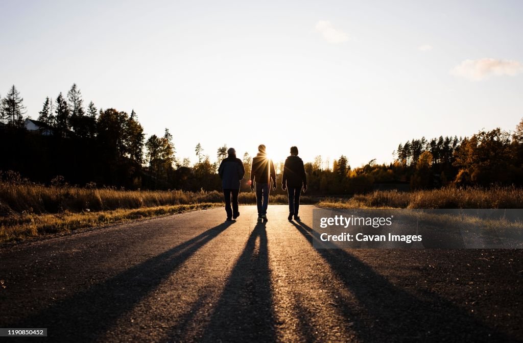 Silhouette of family walking down a country road at sunset