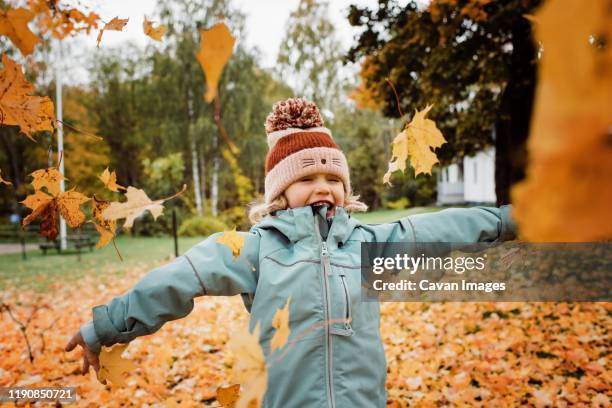 young girl laughing and throwing fall leaves into the air - música cinematográfica fotografías e imágenes de stock