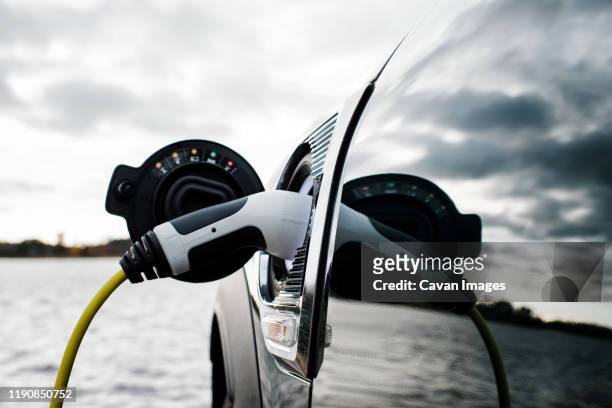 electric car charging socket and lead by the beach - electric cars stockfoto's en -beelden