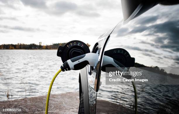 mini electric car charging socket and lead by the beach - car electro stock pictures, royalty-free photos & images