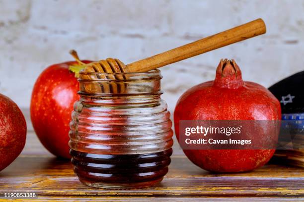 pouring honey on apple and pomegranate with honey symbols of jewish new year - rosh hashanah. - shofar stock pictures, royalty-free photos & images