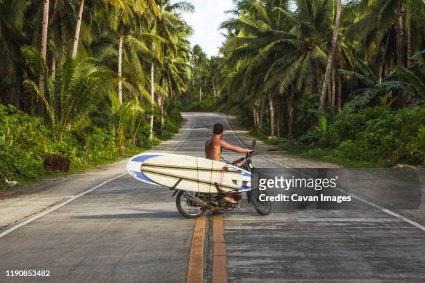 man riding motorcycle with surfboards in coconut road palms philippine - vietnam beach stockfoto's en -beelden
