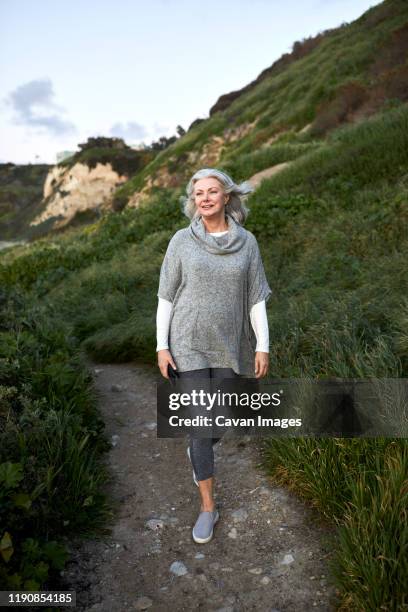 full length of senior woman walking on footpath at manhattan beach during sunset - woman standing full length stock pictures, royalty-free photos & images