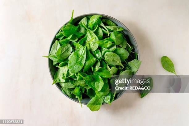 Bowl of fresh Baby spinach leaves over white marble background. Flat lay. Copy space.