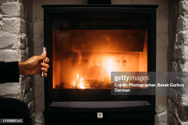 a man closing the door of the fireplace - kaminfeuer stock-fotos und bilder