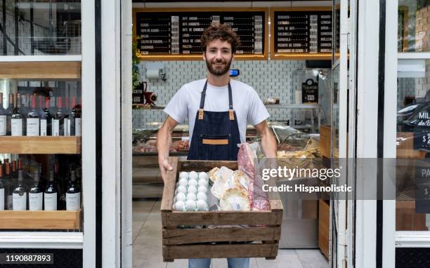livreà livrer à une dielle retenant une boîte avec des produits pour un client souriant à l'appareil-photo - boucherie photos et images de collection