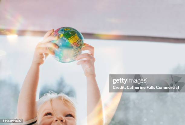 child holding globe ball - child globe stock-fotos und bilder