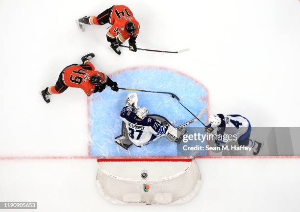 Connor Hellebuyck and Neal Pionk of the Winnipeg Jets defend against Sam Steel and Max Jones of the Anaheim Ducks during the first period of a game...