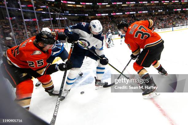 Nick Ritchie and Ondrej Kase of the Anaheim Ducks battle Adam Lowry of the Winnipeg Jets for a loose puck during the first period of a game at Honda...