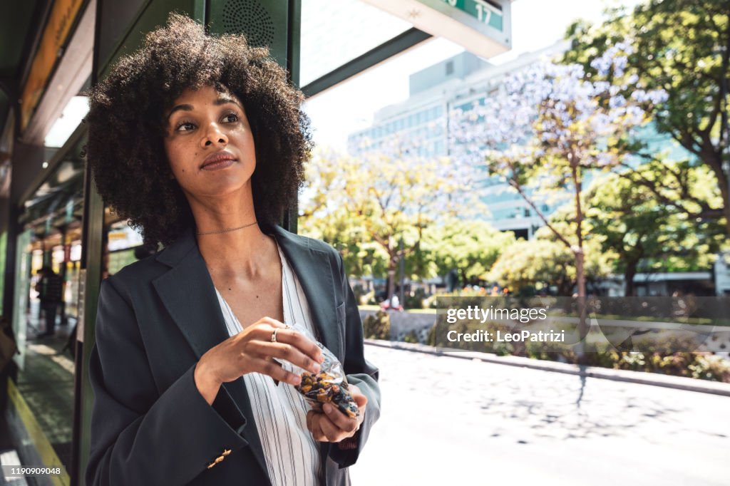 Mulher americana afro do negócio no batente de barra-ônibus na baixa