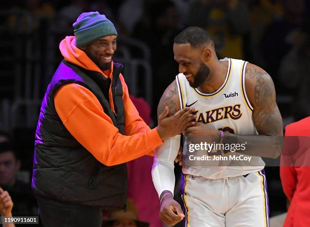 LeBron James of the Los Angeles Lakers has a moment on the sideline with former Laker Kobe Bryant in the second half during a game against the Dallas...