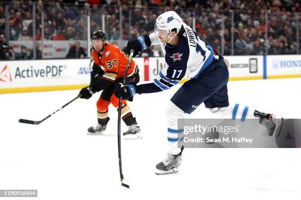 Adam Lowry of the Winnipeg Jets shoots the puck as Nick Ritchie of the Anaheim Ducks looks on during the second period of a game at Honda Center on...