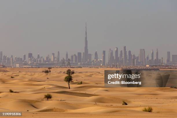 The Burj Khalifa skyscraper, center, stands above other skyscrapers on the city skyline beyond desert sands in Dubai, United Arab Emirates, on...