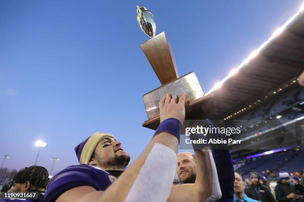 Jacob Eason of the Washington Huskies holds the Apple Cup trophy after defeating the Washington State Cougars 31-13 during their game at Husky...