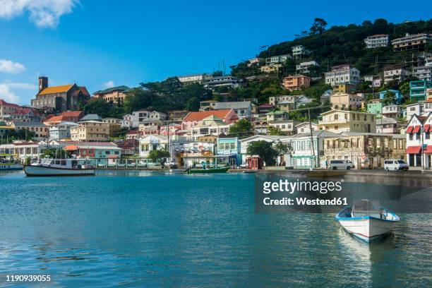 motorboat in harbor against residential district of st georges, caribbean - saint georges foto e immagini stock