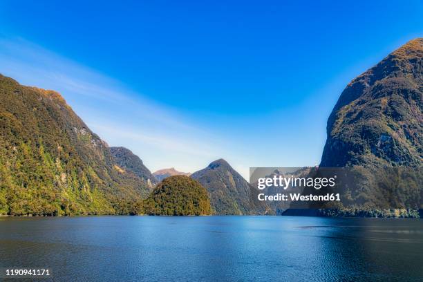 scenic view of doubtful sound against blue sky in fiordland national park at te anau, south island, new zealand - te anau stock pictures, royalty-free photos & images