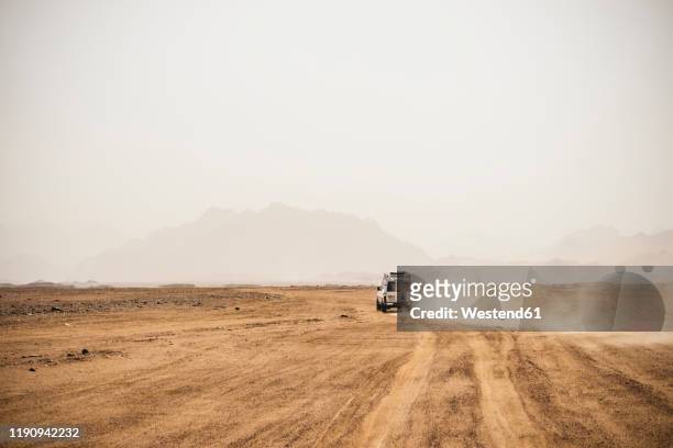 off-road vehicle moving on arid landscape against clear sky during sunny day, suez, egypt - arid stock pictures, royalty-free photos & images