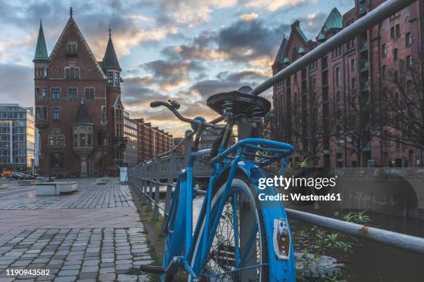 bicycle parked on footpath against speicherstadt at sunset, hamburg, germany - raduno stock-fotos und bilder