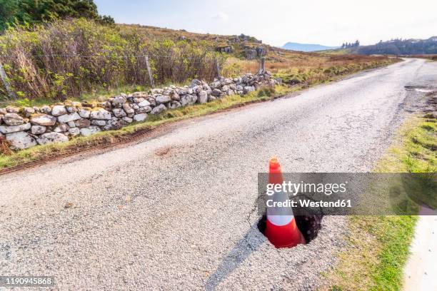 traffic cone in pot hole on road at isle of skye, highlands, scotland, uk - pothole stockfoto's en -beelden