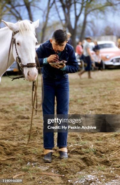 General view of a young boy stuffing his face with a blueberry pie after an event at Gymkhana, which is an equestrian event consisting of speed...