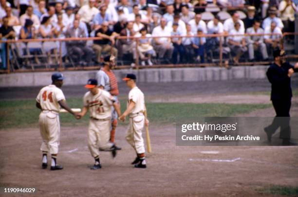 Eddie Mathews of the Milwaukee Braves is congratulated by the batboy and his teammate Hank Aaron after hitting a homerun during an MLB game against...