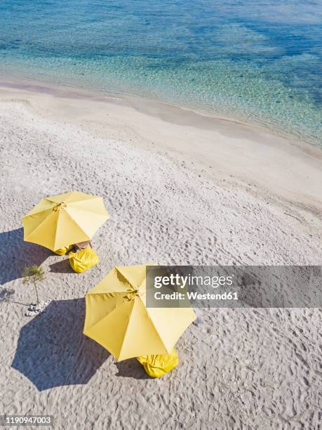 drone shot of yellow parasols at beach during sunny day, gili-air island, indonesia - sonnenschirm stock-fotos und bilder