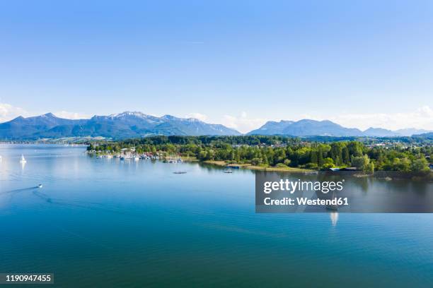 germany, bavaria, prien am chiemsee, sailboats sailing near shore of chiemsee lake with chiemgau alps in background - lake chiemsee stock pictures, royalty-free photos & images
