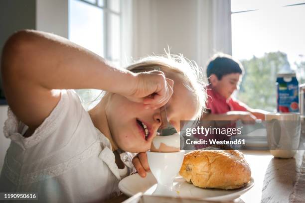 girl eating a boiled egg at dining table - children eating breakfast stock-fotos und bilder