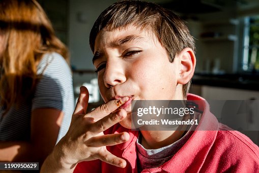 Portrait of boy at home licking his finger Portrait of boy at home licking his finger