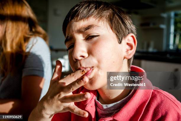 portrait of boy at home licking his finger - trying stockfoto's en -beelden