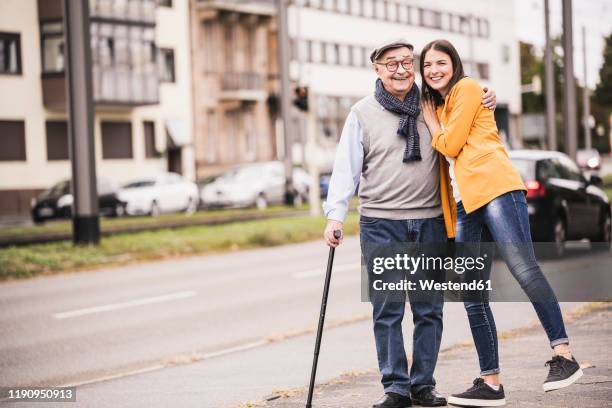 portrait of happy senior man strolling with his adult granddaughter - old man young woman stock-fotos und bilder