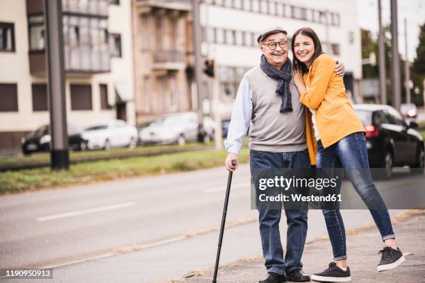 portrait of happy senior man strolling with his adult granddaughter - old man young woman stockfoto's en -beelden
