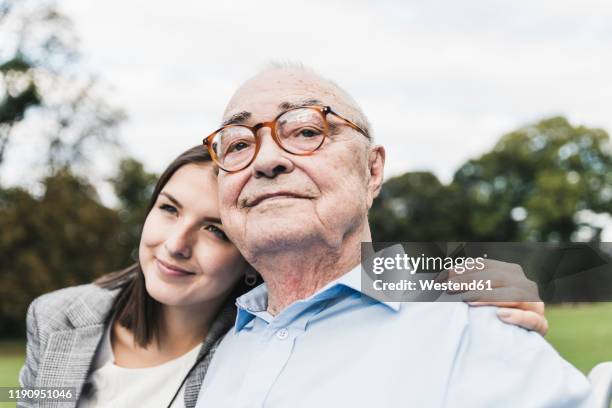 portrait of self-confident senior man with his granddaughter in a park - alzheimer's disease stock-fotos und bilder