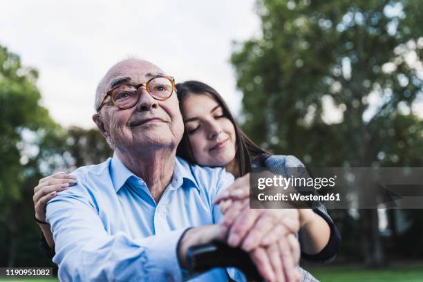 portrait of senior man with his granddaughter in a park - old man young woman stockfoto's en -beelden