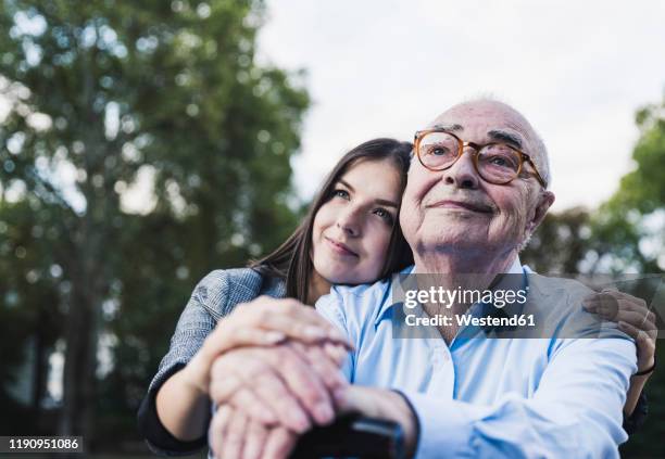 portrait of senior man and his granddaughter in a park - dementia stock-fotos und bilder